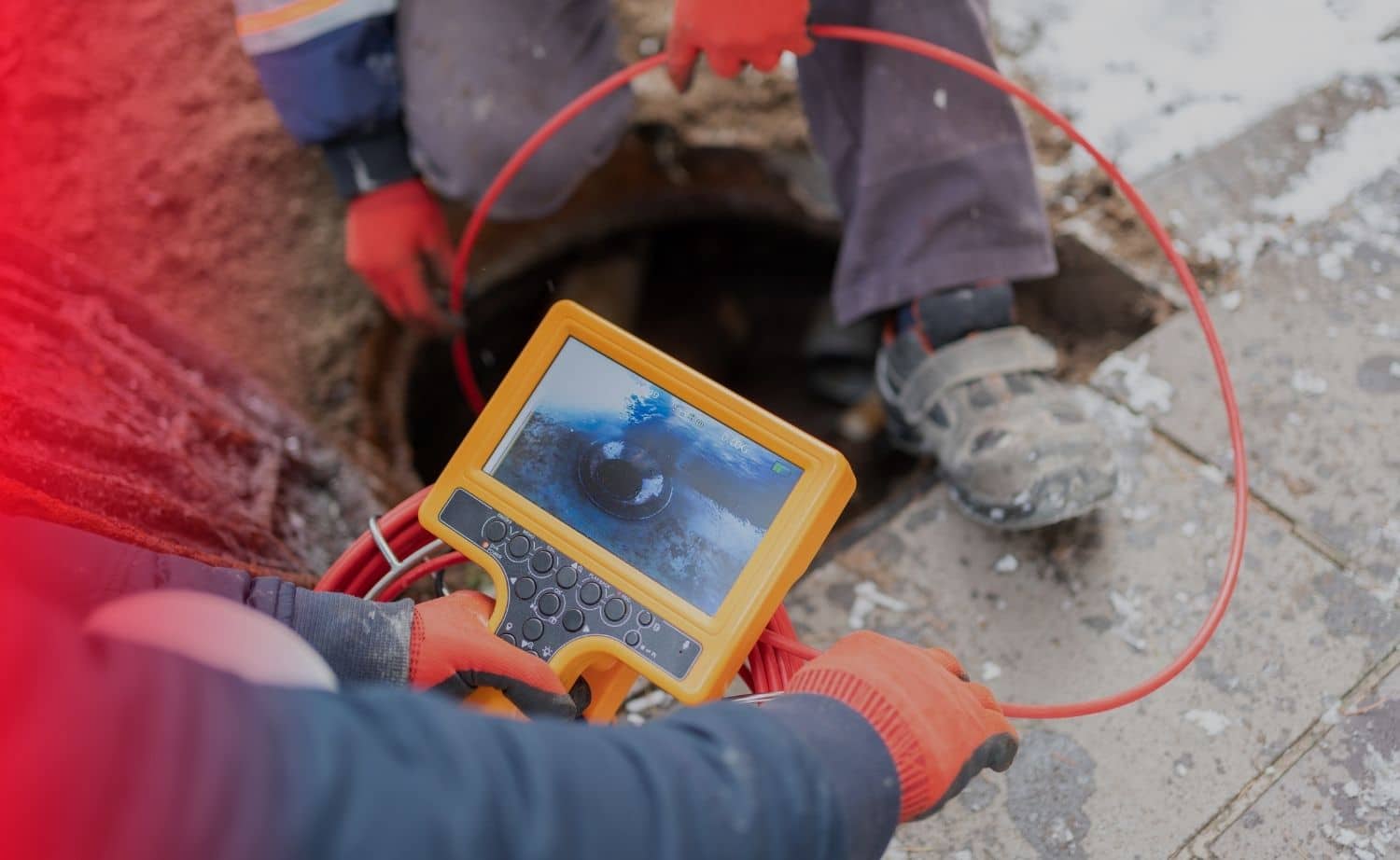 Technician monitoring a sewer scope camera feed at a manhole access point